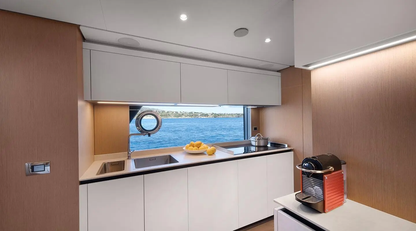 Spica yacht galley interior with white cabinets and a view of the sea through a window