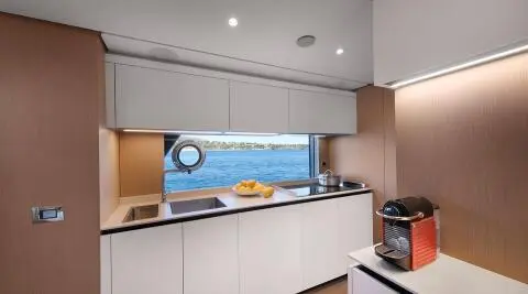 Spica yacht galley interior with white cabinets and a view of the sea through a window