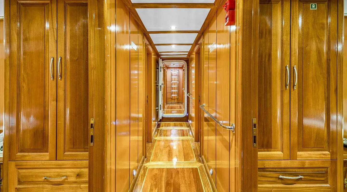 Inside a polished wooden yacht corridor with glossy floors and warm lighting