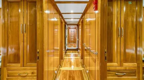 Inside a polished wooden yacht corridor with glossy floors and warm lighting