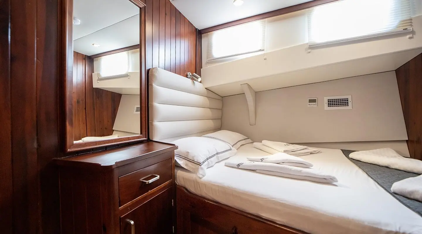 Ulucinar gulet interior: double cabin with porthole, built-in bed, wooden panels