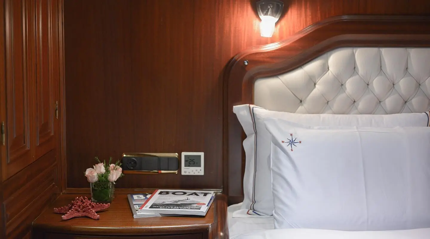 White pillows on a bed with a wood-paneled wall in a yacht cabin interior.