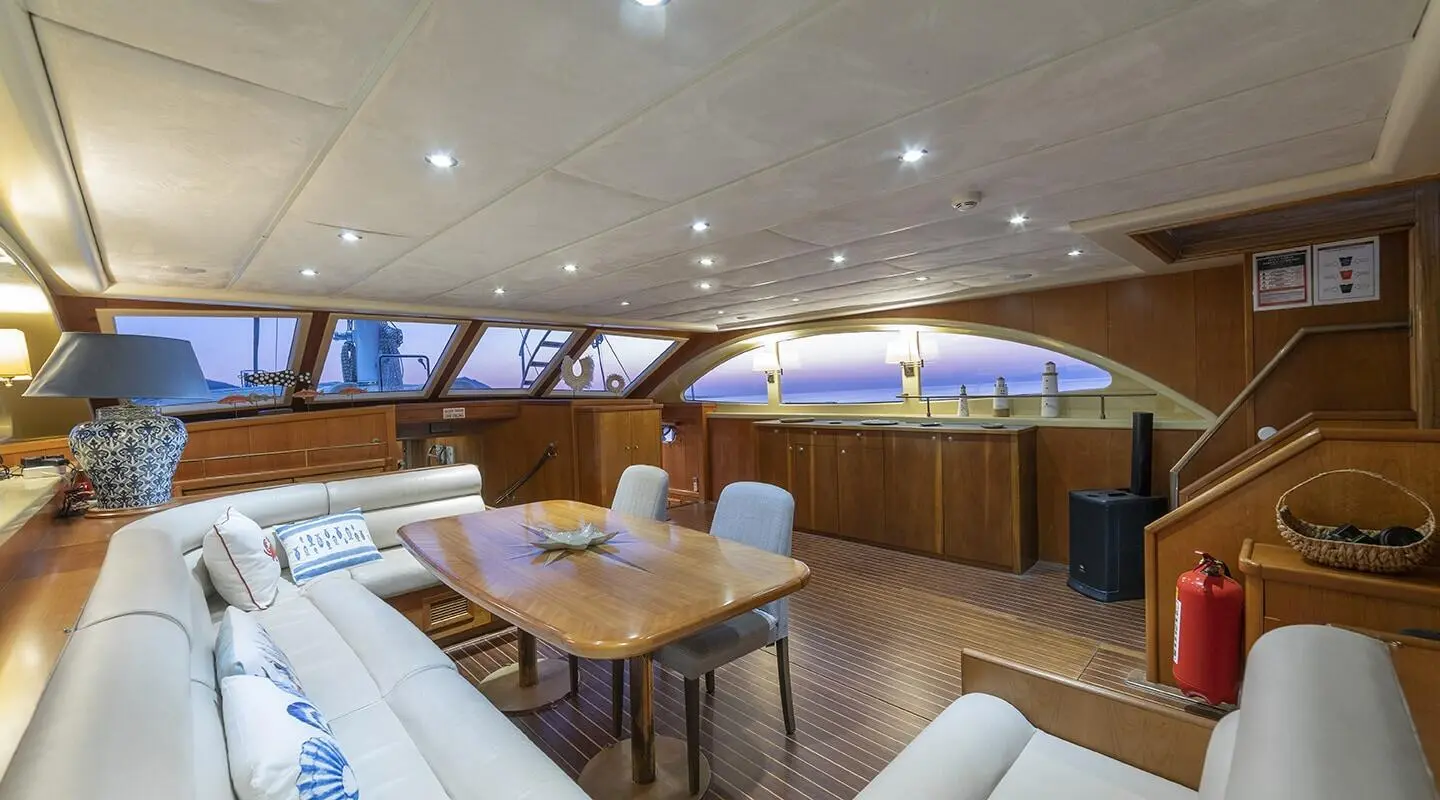 Queen Of Sea yacht interior: cozy seating, wood table, curved bar, warm lighting