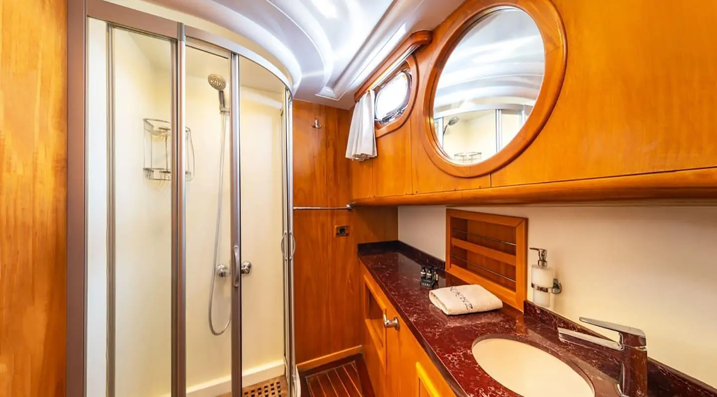 Wood-paneled luxury yacht cabin with shower enclosure and marble sink