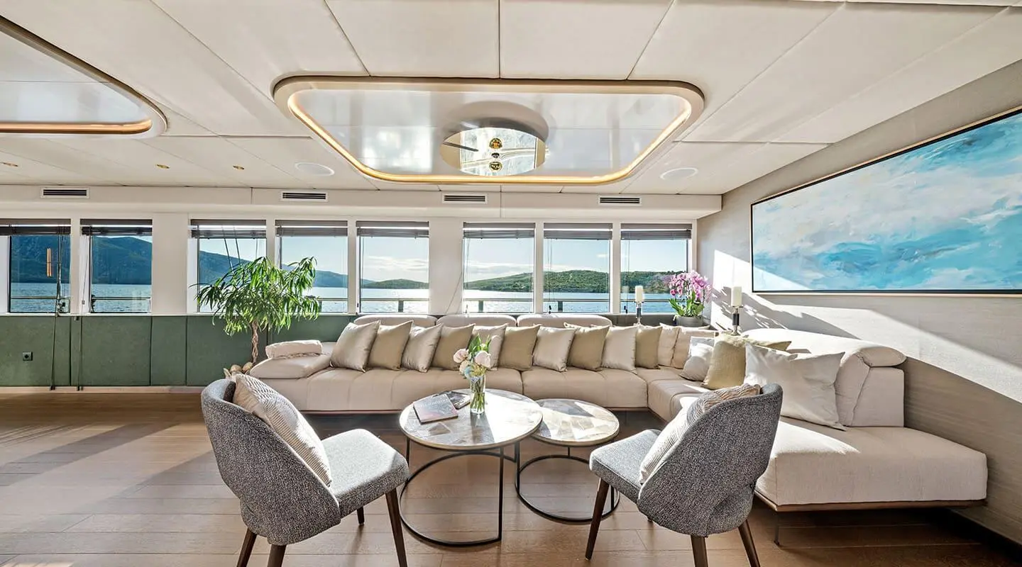 Anima Maris interior lounge with beige sectional and two gray chairs overlooking sea view