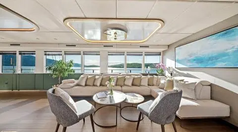 Anima Maris interior lounge with beige sectional and two gray chairs overlooking sea view
