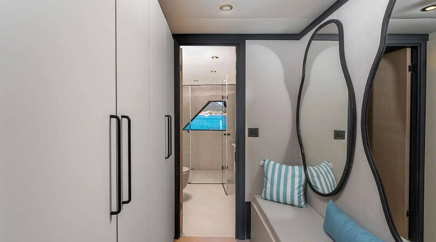 Interior of a yacht bathroom with circular window, blue towels, and white tiled walls