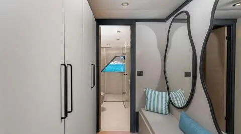 Interior of a yacht bathroom with circular window, blue towels, and white tiled walls