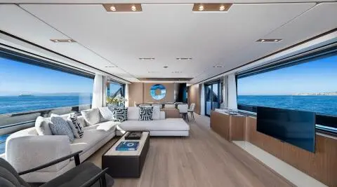 Inside yacht Spica lounge with cream seating, wooden deck, and glass doors