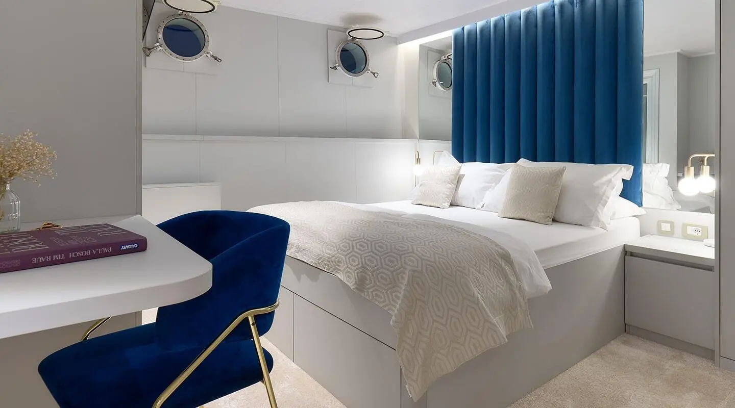 Bedroom aboard with blue curtains, white bedding and bedside tables