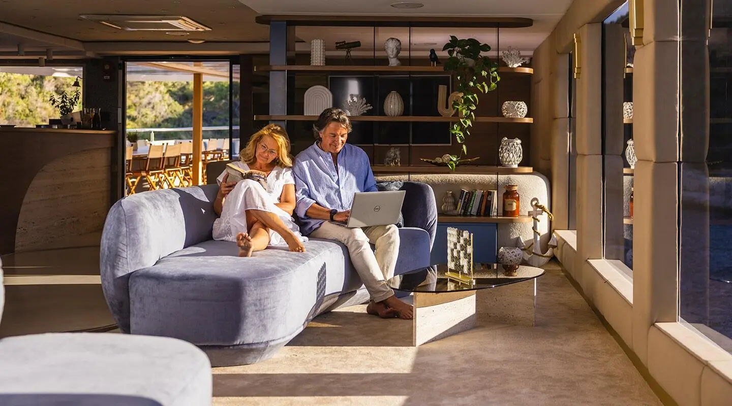 Luxurious Bella yacht salon with guests seated on modern sofas near shelves