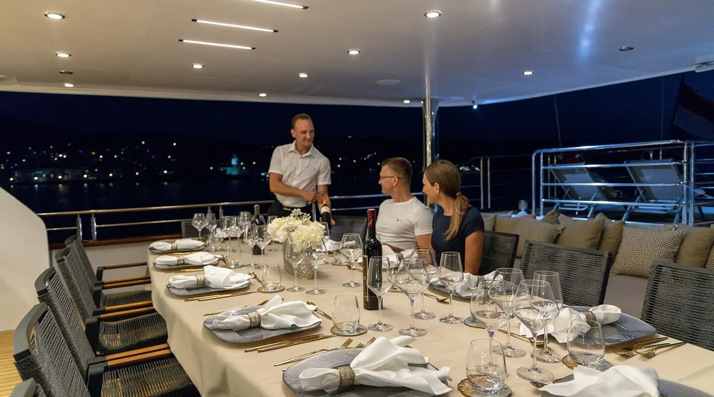 Love Story yacht: elegant dining table aboard sunset-lit luxury gulet at twilight