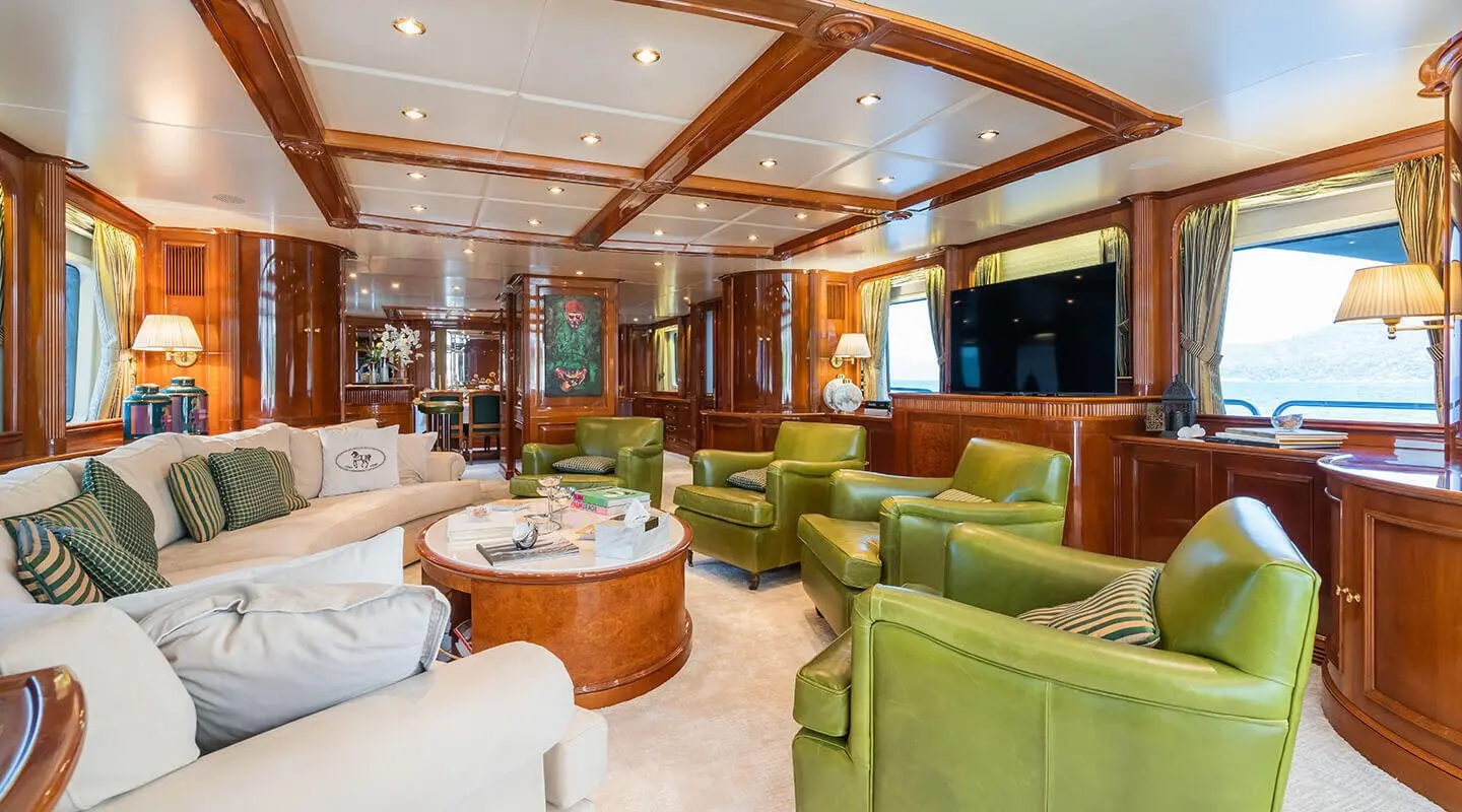 Amadea yacht interior with green and white seating, wood accents, and warm lighting