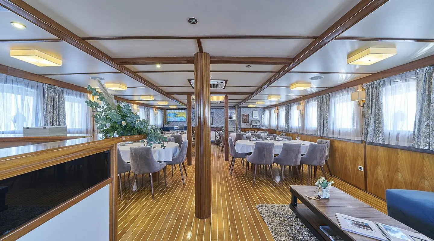 Interior of Amorena luxury yacht with wooden deck, seating, and large windows