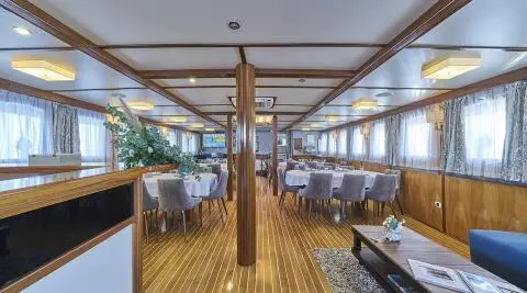 Interior of Amorena luxury yacht with wooden deck, seating, and large windows