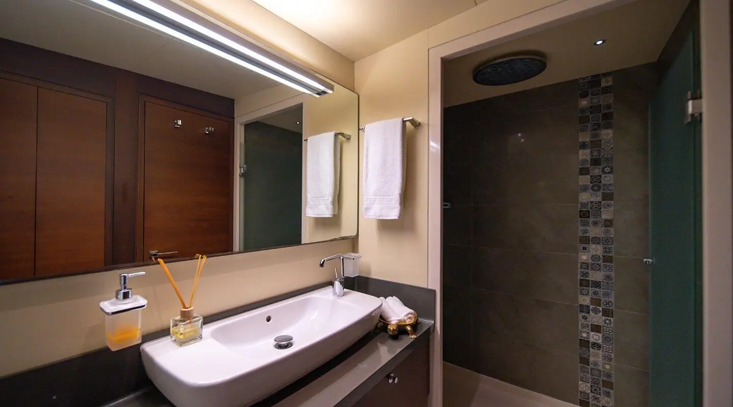 Bathroom with a long sink, mirrored cabinets, and towels; shower area in the back