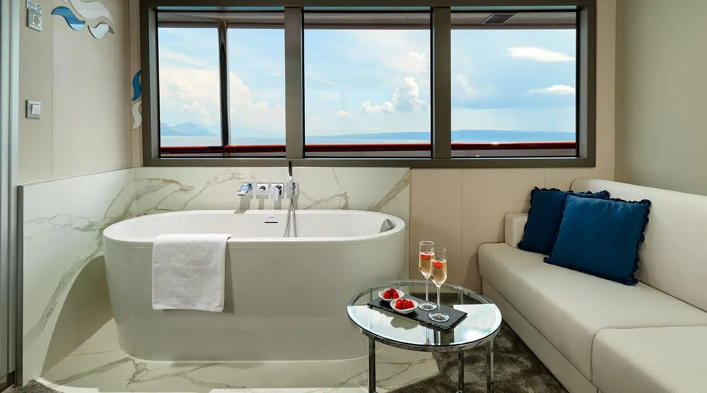 Ohana yacht interior: master cabin with bed, seating area, windows, and a small table