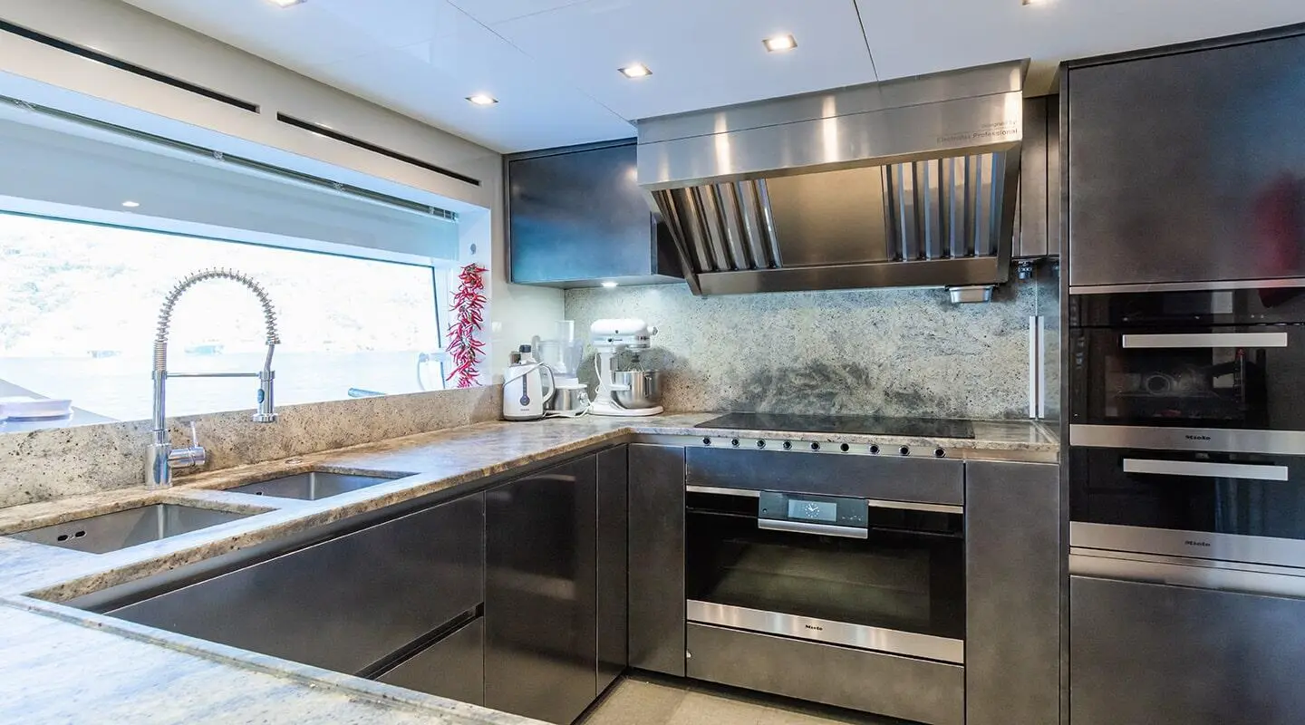 Takara One yacht kitchen with stainless steel appliances and dark cabinetry