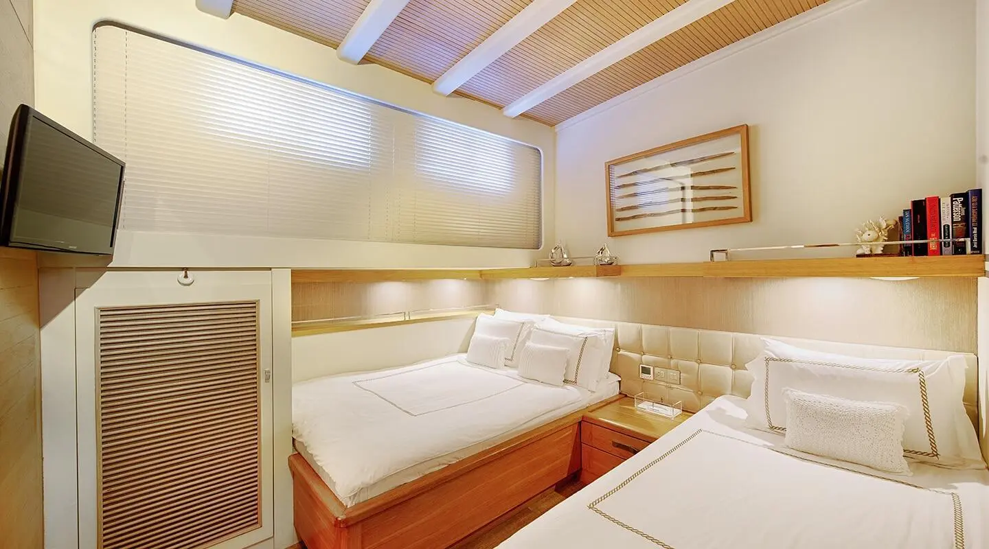 Luxurious twin-berth cabin aboard a yacht with white bedding and wood accents