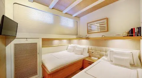 Luxurious twin-berth cabin aboard a yacht with white bedding and wood accents
