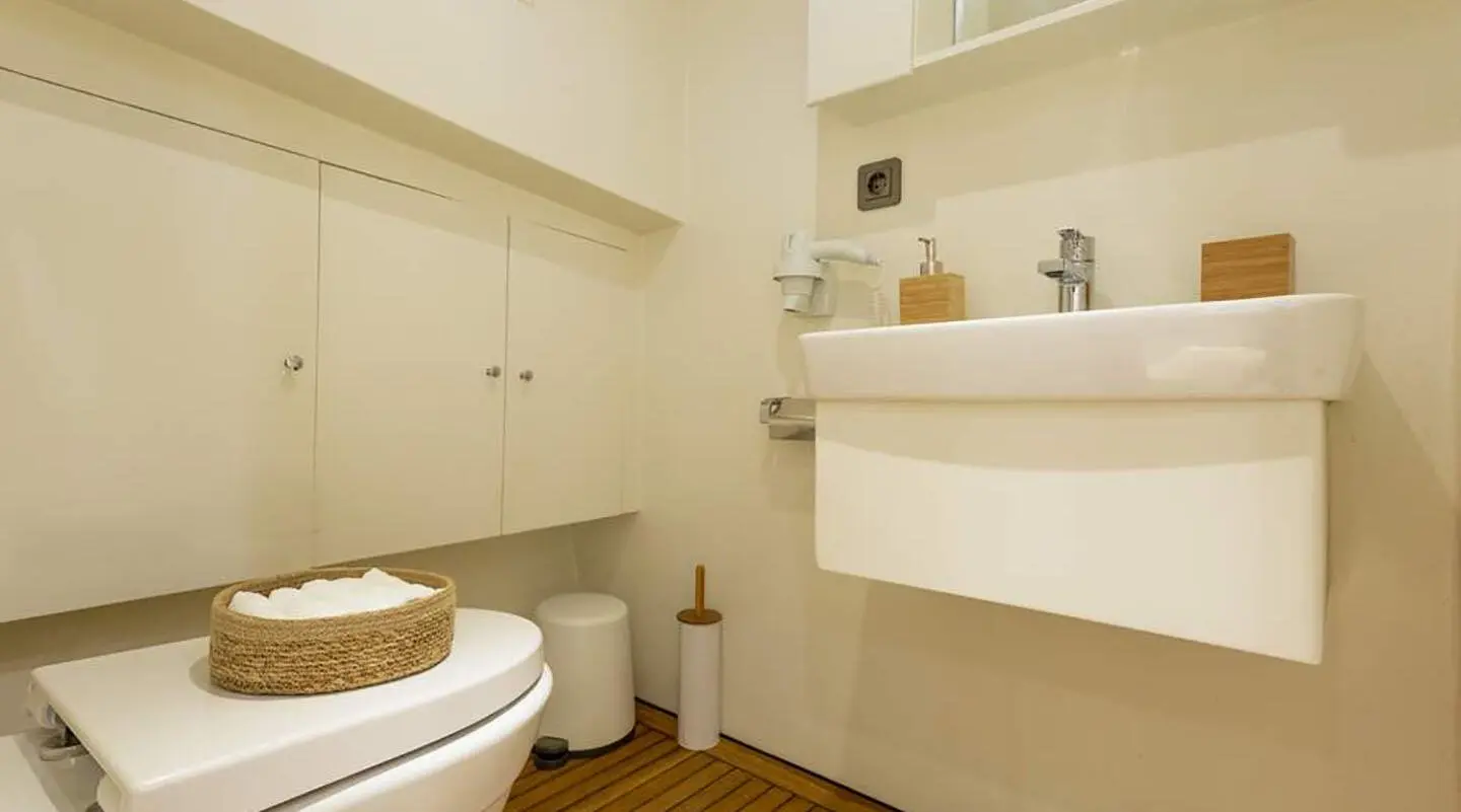 Small bathroom on Grand Sailor gulet with white fixtures and wooden floor