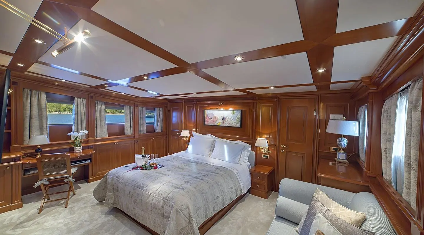 Aquila luxury yacht master cabin with two beds, wooden paneling, and dimmed lighting
