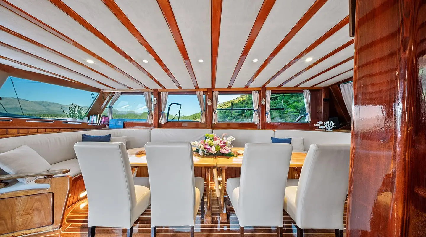 Elegant yacht Eleganza under a striped awning with seating and glass table on deck