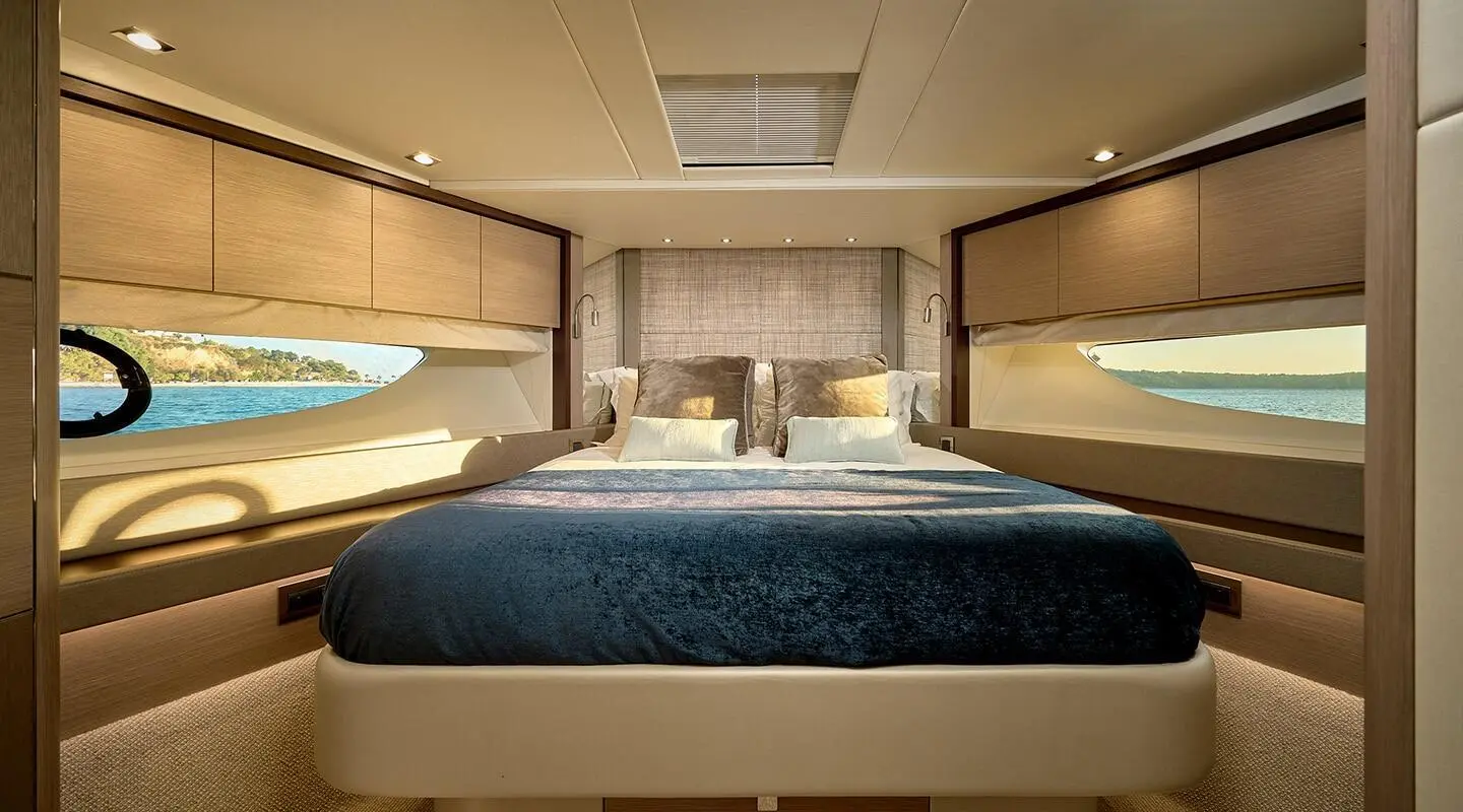 View of a yacht cabin with a large bed, overhead storage, and soft lighting