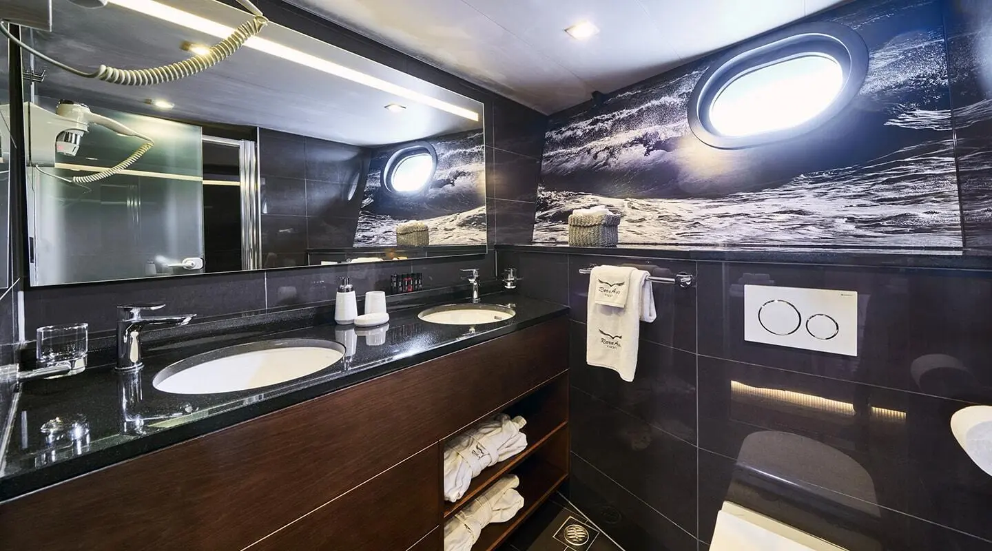 Interior of a luxury yacht galley with dark wood cabinets and shelves