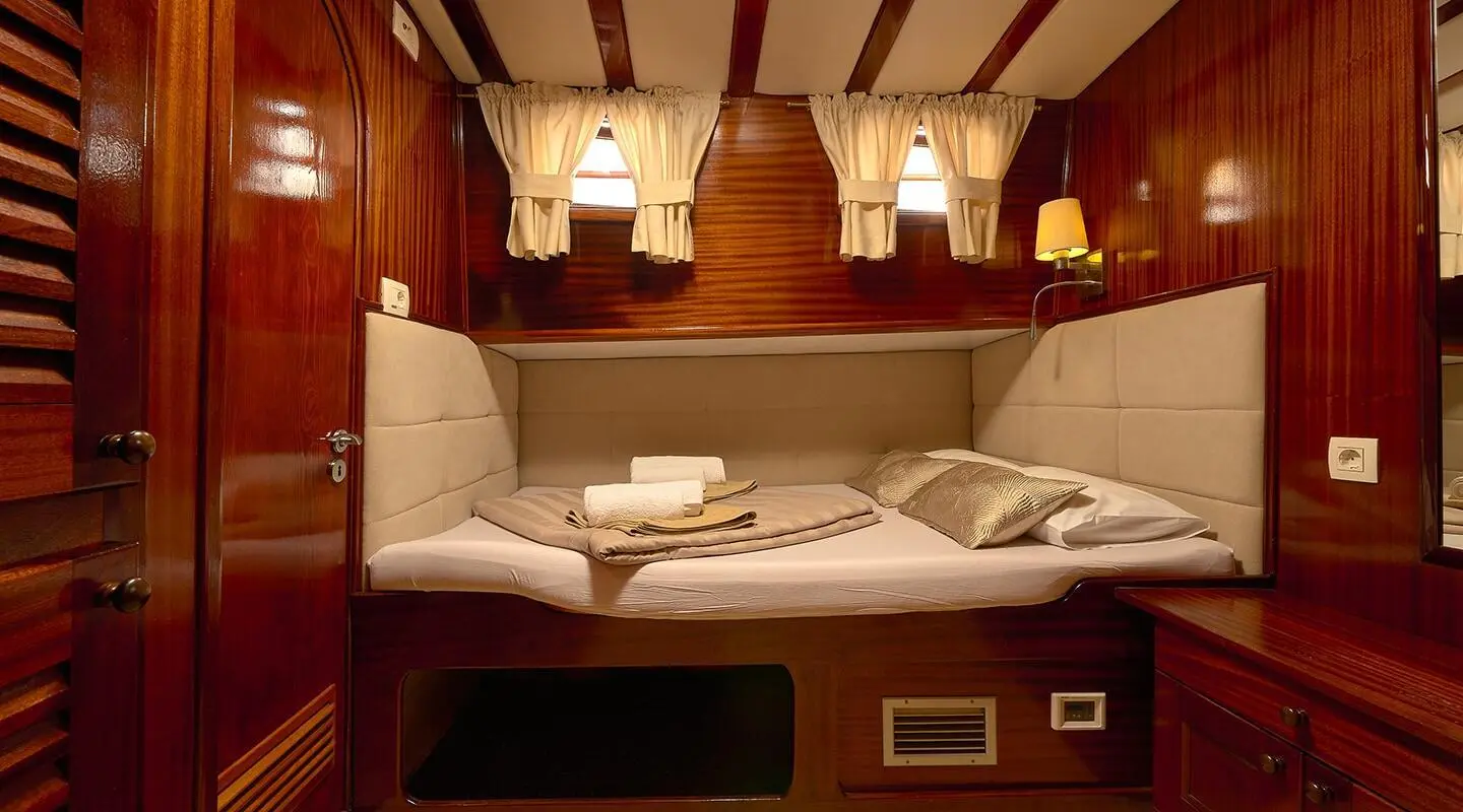 Linda yacht interior: cozy bunk bed cabin with white bedding and warm lighting