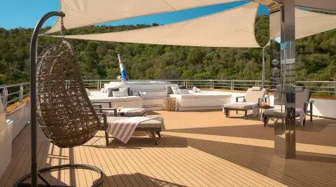 Cristal yacht deck with sun loungers, shaded seating, and a blue canopy