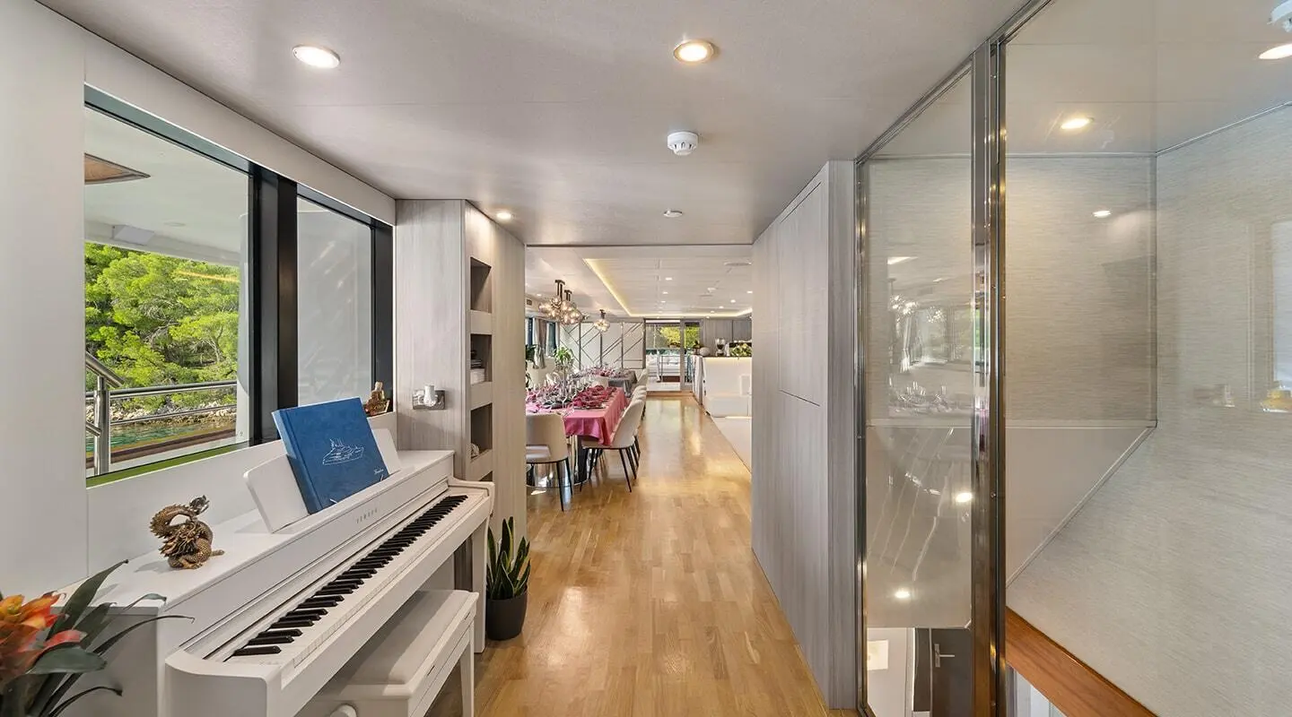 Luxurious yacht salon with a white piano and large windows overlooking greenery