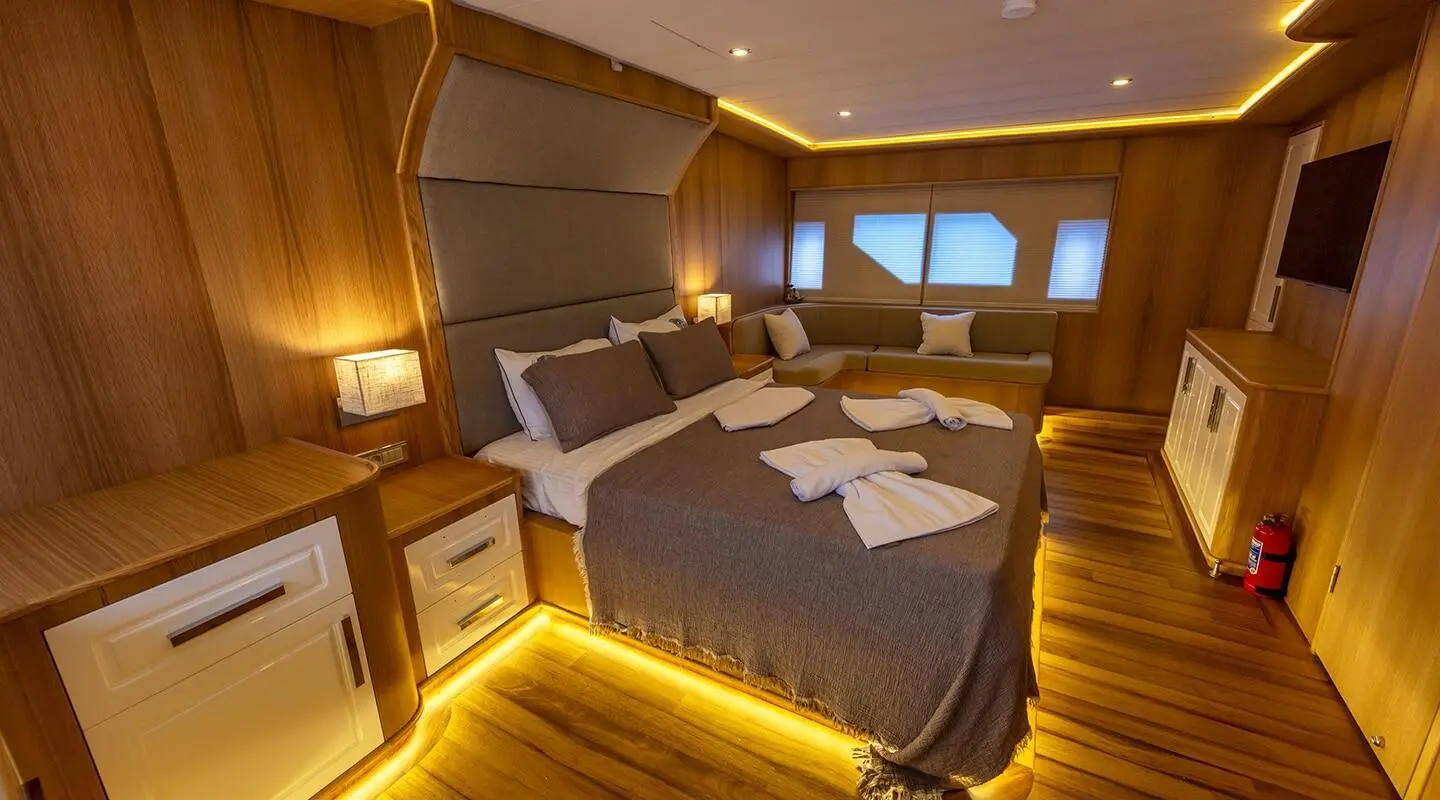 Cozy wood-paneled bedroom aboard yacht with large bed and soft lighting