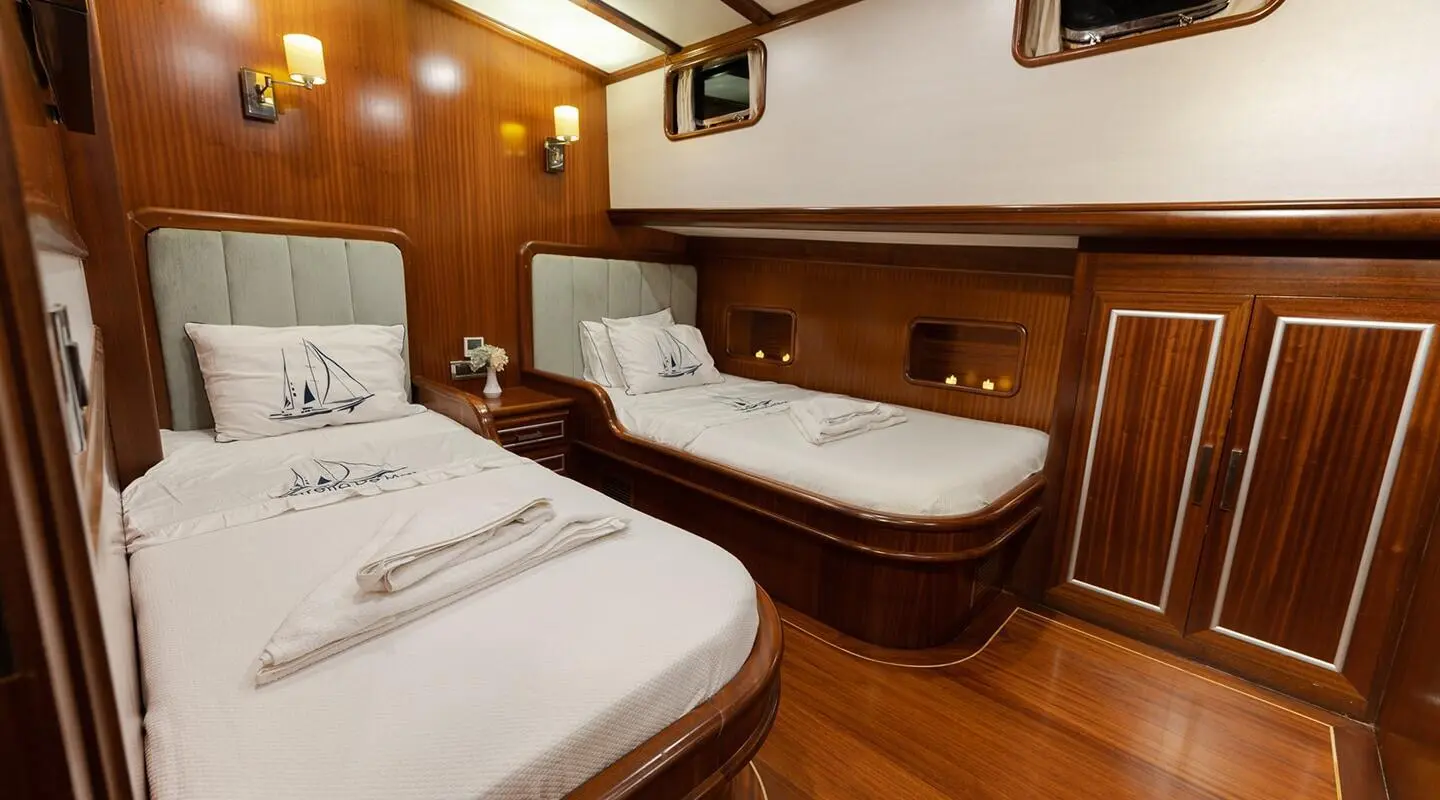 Interior of Estrella De Mar yacht: twin beds, warm wood panels, evening lighting