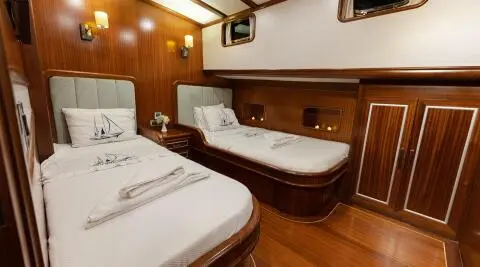 Interior of Estrella De Mar yacht: twin beds, warm wood panels, evening lighting