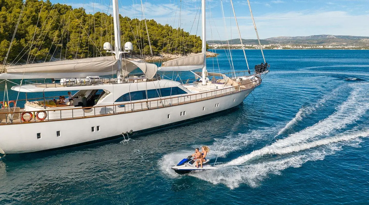 Gulet Alessandro I yacht anchored with people swimming near bow in blue harbor