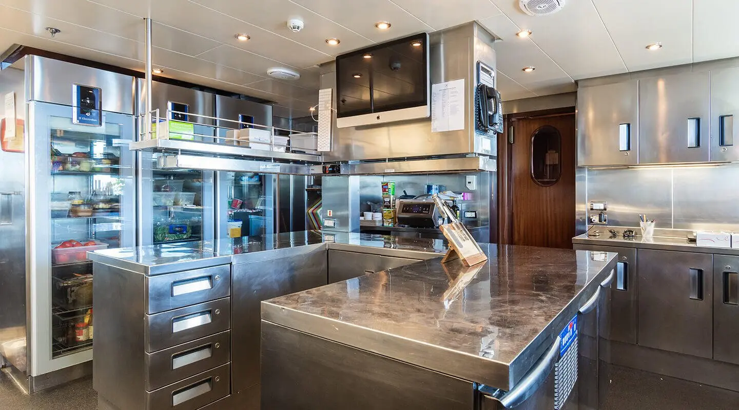 Apogee yacht interior: stainless steel galley with marble countertop and modern appliances