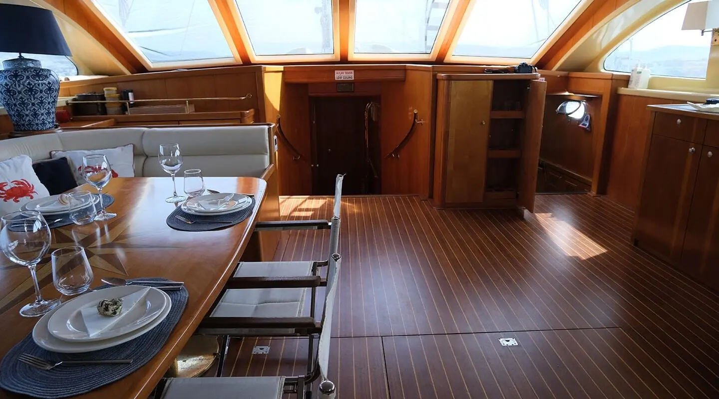 Queen Of Sea yacht interior showing polished wood deck and seating area bathed in sunset light