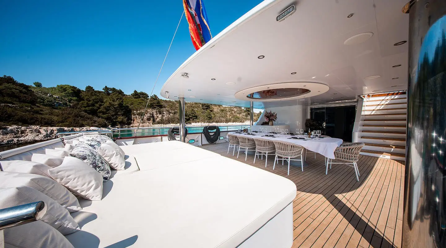 Nocturno yacht outside deck with dining table and lounge cushions in sunny weather