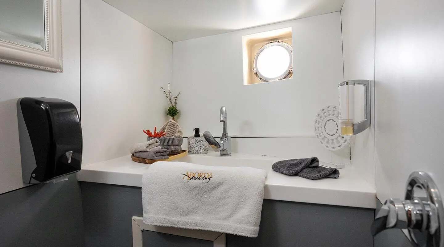 Small boat bathroom with white counter, towel, and sink, plus soap dispenser and decor