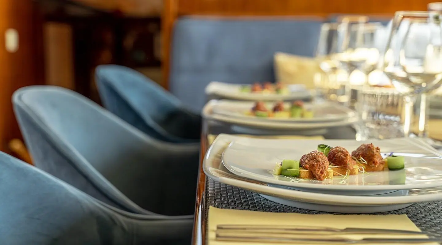 Sunlit yacht dining on deck with blue cushions and plates set for service
