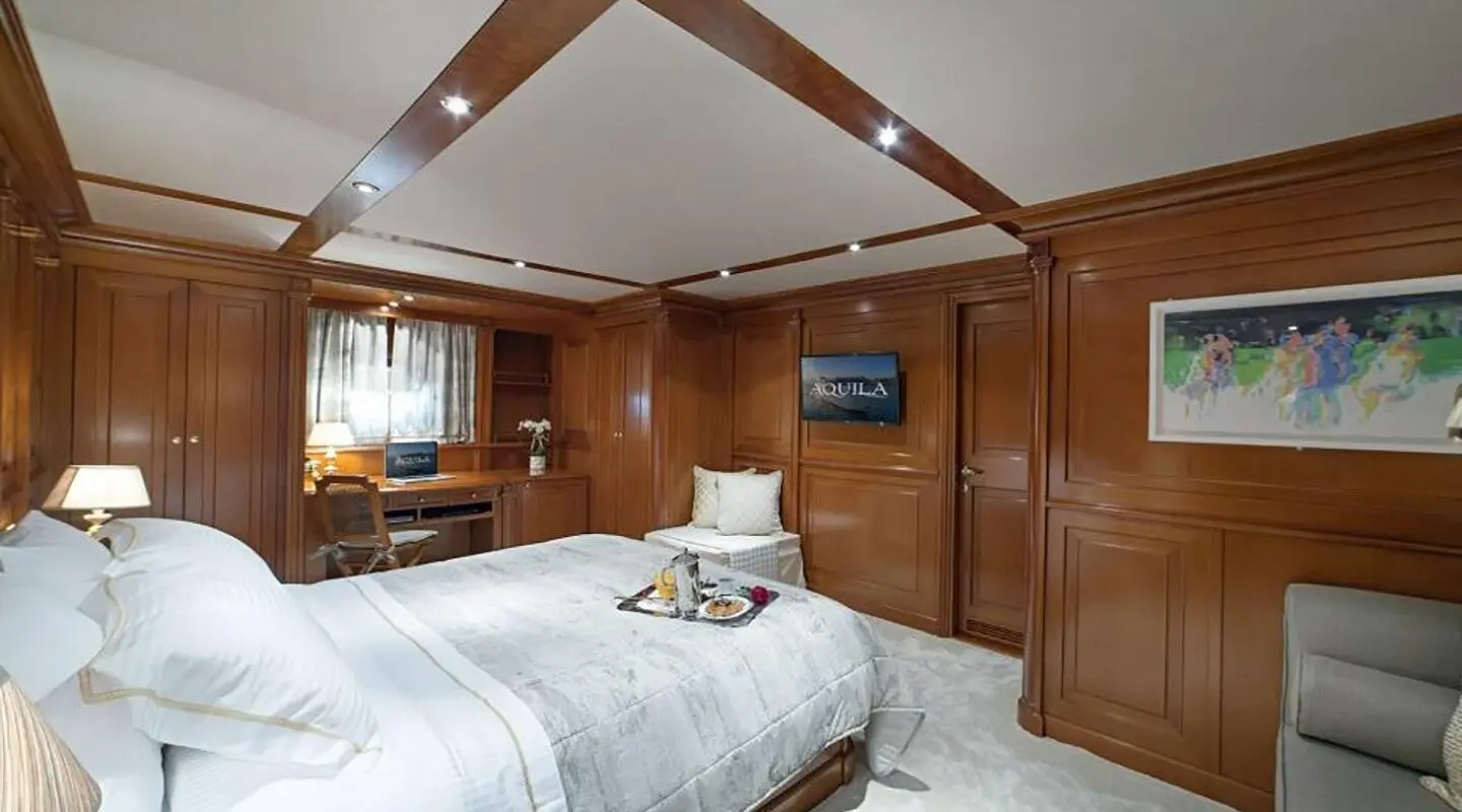 Aquila interior: cozy bedroom with wooden panels, bed, and bedside lamps