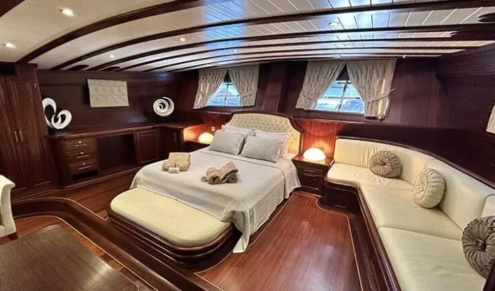 Luxurious master cabin with king bed, cream upholstery, wood floors, ceiling windows