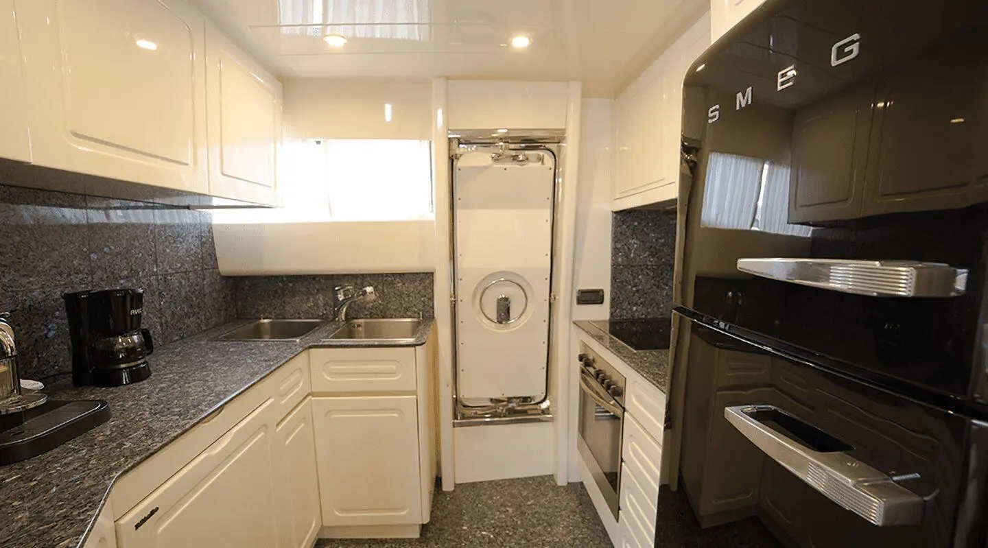 A compact yacht galley aboard Amoraki with white cabinets and stainless appliances
