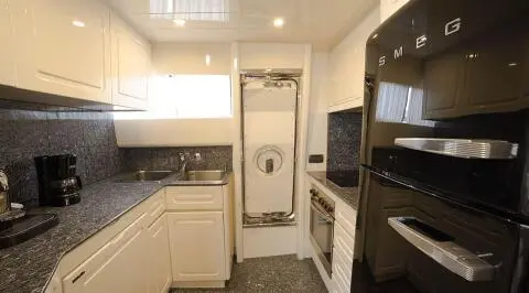 A compact yacht galley aboard Amoraki with white cabinets and stainless appliances