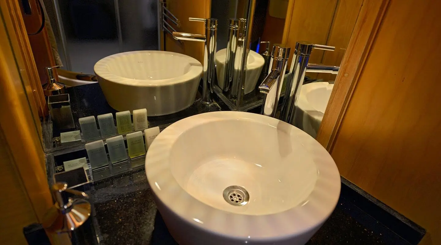 White round sink with faucet and mirror reflection on a glossy bathroom counter