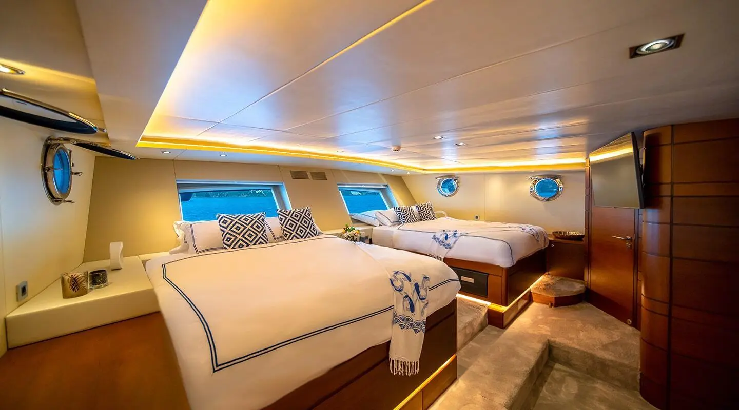 Luxurious yacht interior with two large beds, wooden accents, and warm ambient lighting