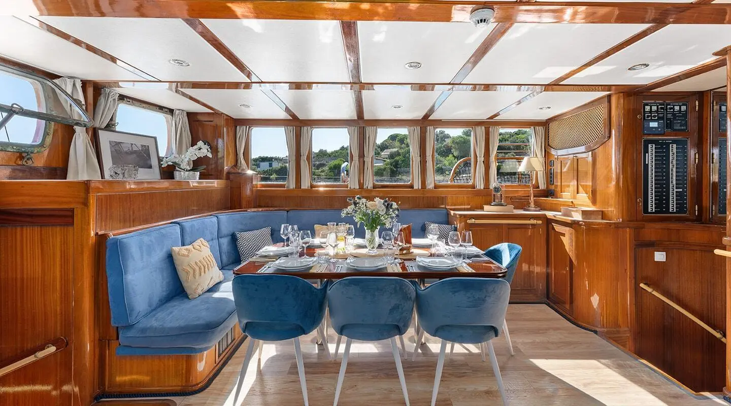 Interior view of a yacht dining area with table set and blue chairs