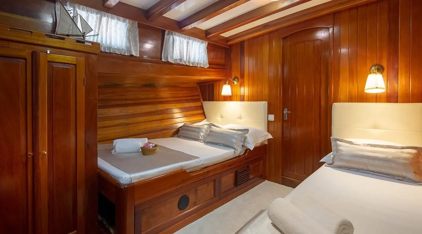 Andi Star gulet interior: wooden cabins with porthole, bed, and storage