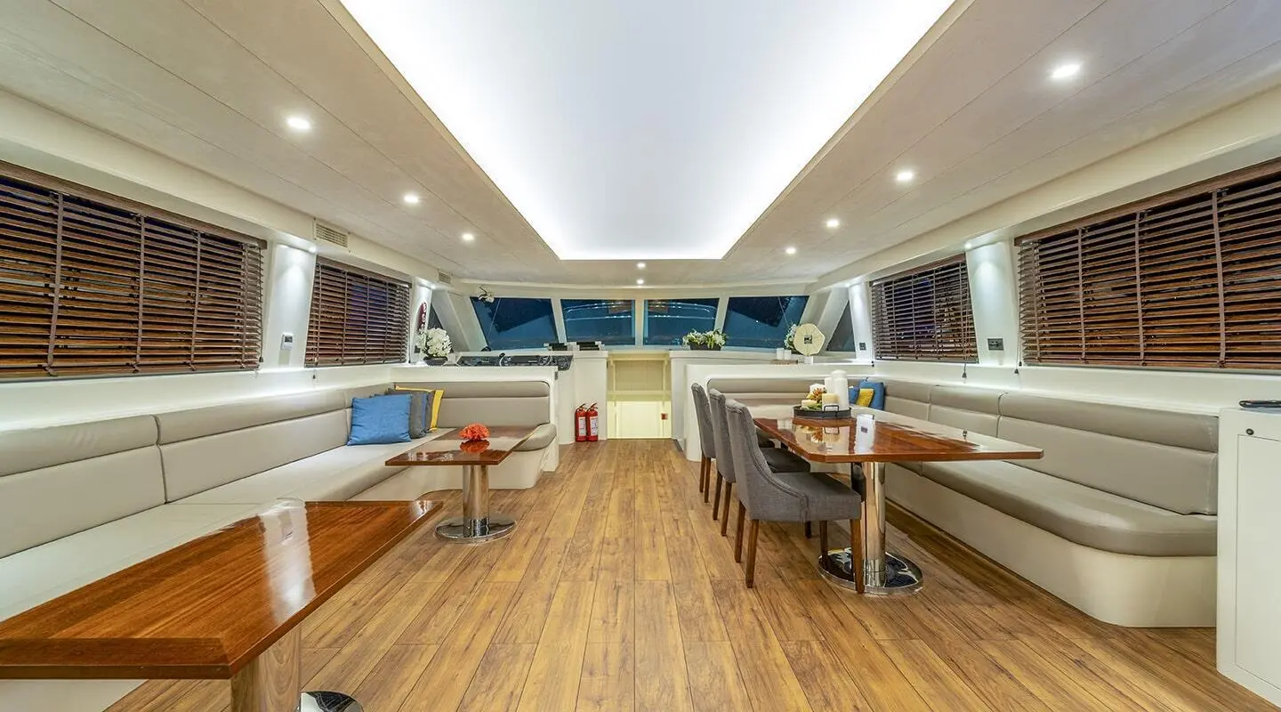 Luxurious yacht interior with wooden floor, seating, and sunlit ceiling